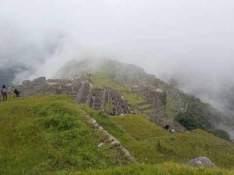       High vantage of the mist-covered Machu Picchu citadel stretching into the clouds
  