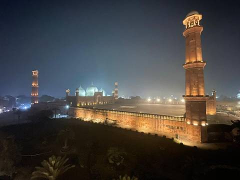       The illuminated Badshahi Mosque and its soaring minarets glow against the Lahore night sky.
  