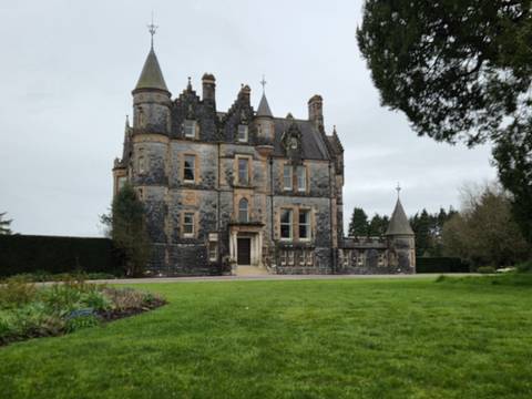       Historic stone castle set amid manicured lawn on an overcast day
  