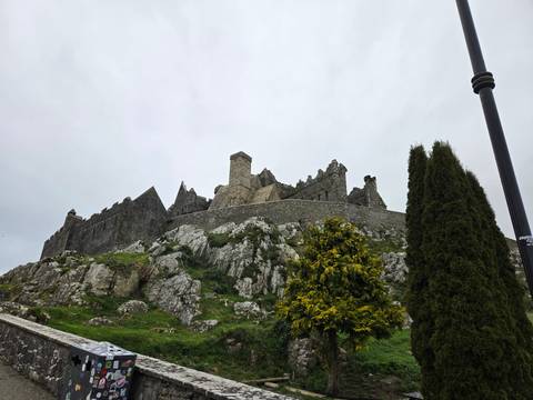       Rock of Cashel fortress rising above rocky hill with cloudy grey sky
  