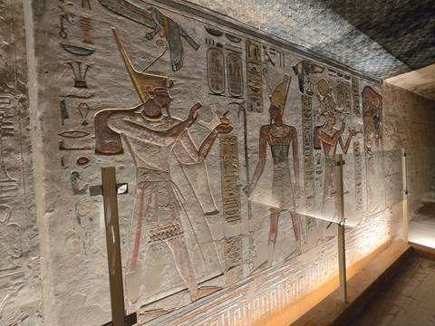       Colorful painted wall relief of ancient Egyptian figures holding objects with hieroglyphs all around
  