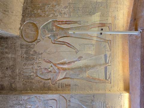       Vertical relief showing two Egyptian deities, one crowned with a solar disk, behind a clear barrier
  