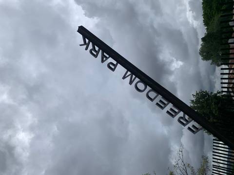       Angled metal sign reading FREEDOM PARK against a backdrop of brooding grey clouds
  