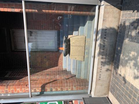       Eternal Flame of Democracy burning in a stone bowl on stepped plinth inside a glass enclosure
  