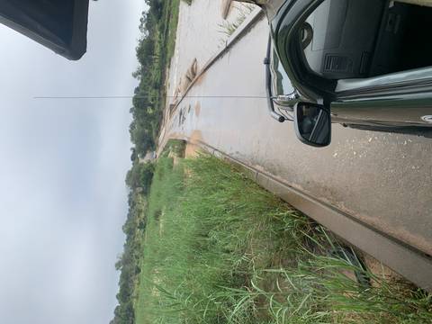       Open safari vehicle on a wet concrete causeway surrounded by green bushland under a grey sky.
  