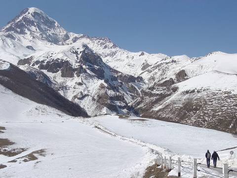       Snow-covered peaks and rugged valleys of the Caucasus under a clear blue sky.
  