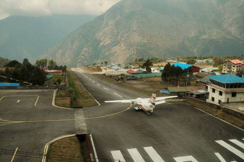       A small aircraft parked on a mountain runway surrounded by steep Himalayan terrain.
  
