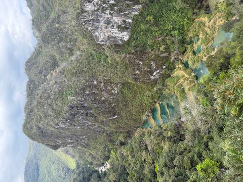       Aerial vista of emerald tiered pools and limestone cliffs of Semuc Champey surrounded by rainforest
  