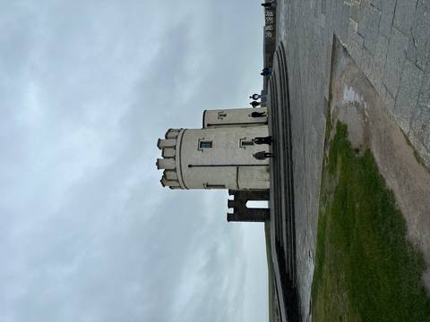       O'Brien's Tower stands on a windswept headland as visitors circle its base under grey skies.
  