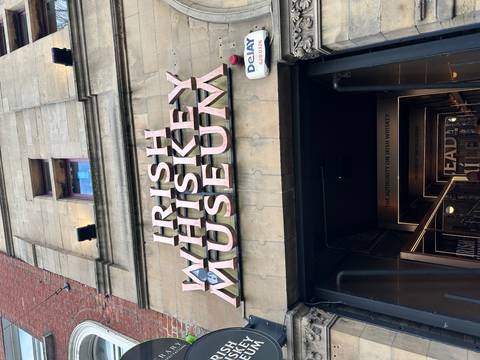       Large entrance sign reading 'Irish Whiskey Museum' above a stone doorway in Dublin.
  