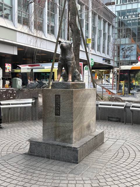       Bronze statue of loyal dog Hachiko on a granite pedestal in a busy urban plaza.
  