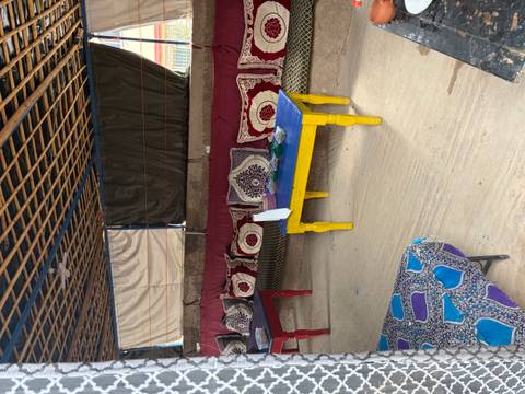       Colorful low tables and cushioned benches arranged inside a shaded nomadic tent lounge.
  