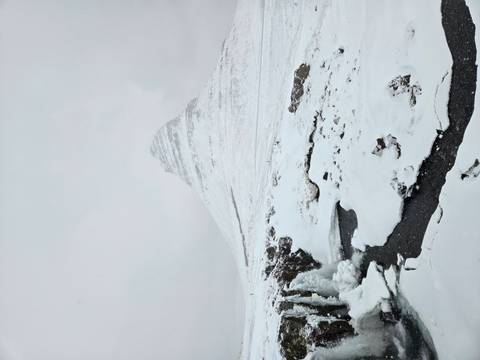       Snow-covered Kirkjufell mountain rises pyramid-like above frozen stream and falls
  