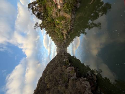       Mirror-like river reflects clouds and forested cliffs in Tasmania's Cataract Gorge
  