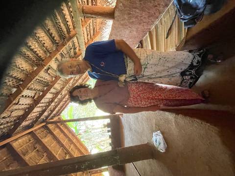       Travelling couple dressed in sarongs inside traditional thatched Sri Lankan house
  