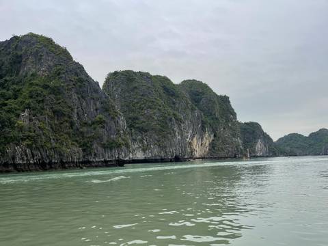       Limestone karst islands rising from calm green waters under an overcast sky
  
