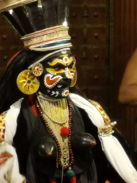      Blurred close-up of a performer in elaborate traditional face paint and ornate jewelry.
  