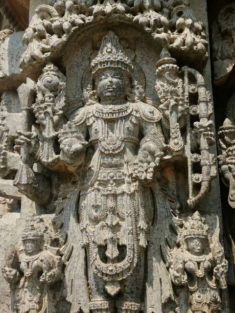       Intricate stone carving of a Hindu deity with ornate jewelry at an ancient temple.
  