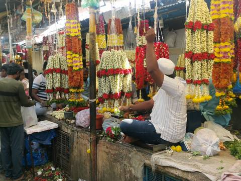      Bustling flower market where vendors hang vibrant garlands of marigolds and roses.
  