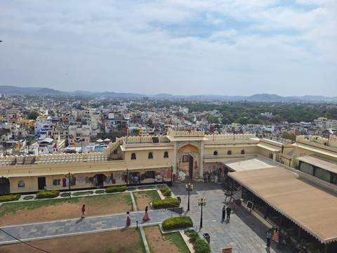       Elevated view across Udaipur cityscape from palace ramparts with hazy hills beyond
  