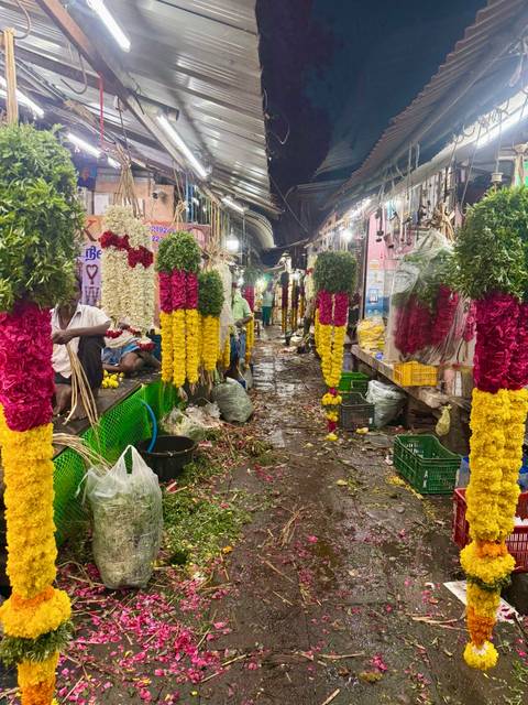       Vibrant Indian flower market alley with hanging garlands of marigold and roses and vendors working
  