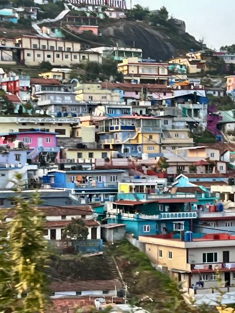       Cluster of brightly painted hillside houses and rooftops create a colourful patchwork in a mountain town.
  