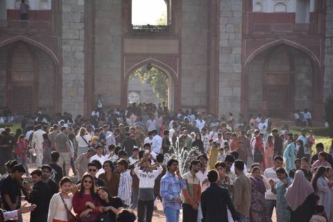       Dense crowd of visitors gathers at the entrance arches of a historic monument in Delhi.
  