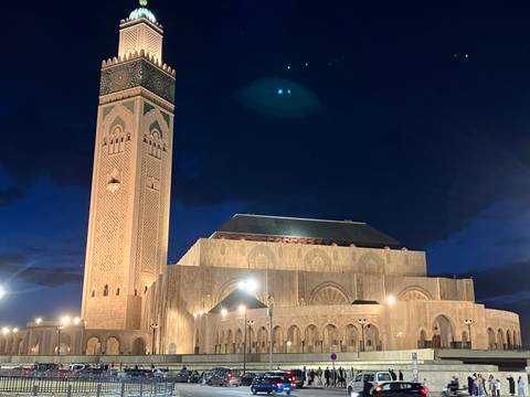       Hassan II Mosque illuminated at night against deep blue sky.
  