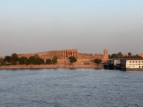       Ancient riverside temple ruins glowing in warm evening light across the Nile
  