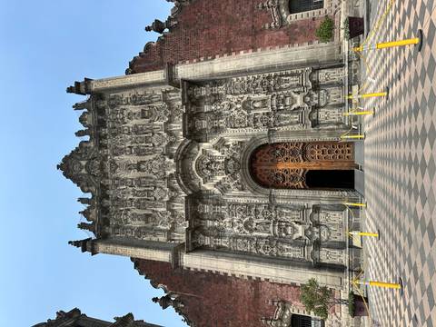       Elaborate stone carvings framing the massive wooden doors of an ornate baroque church in Mexico
  