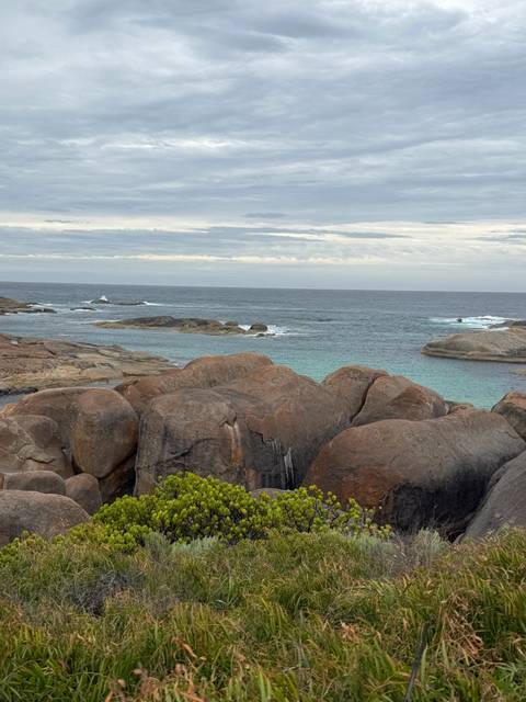       Rocky coastal scene with turquoise water under a cloudy sky in Western Australia.
  
