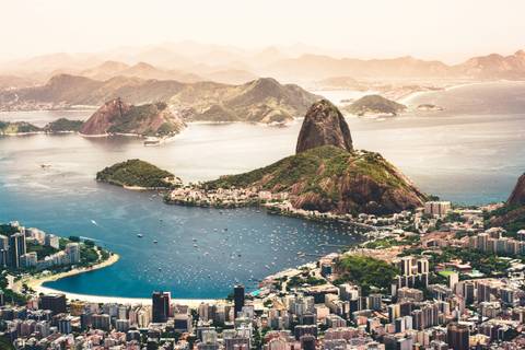       Aerial panorama of a bay with Sugarloaf mountain and sprawling cityscape surrounded by mountains
  