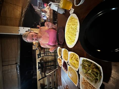       Woman enjoys a table full of Sri Lankan curries and rice in a cozy restaurant.
  