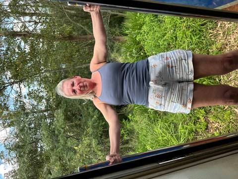       Woman leans out of a slow-moving Sri Lankan train enjoying jungle scenery.
  
