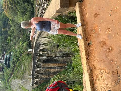       Traveler points toward the iconic Nine-Arch Bridge spanning a verdant gorge near Ella.
  