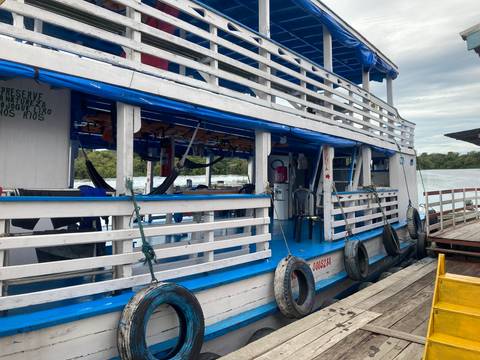       Side view of two-deck Amazon riverboat with hammocks hanging and tires as bumpers
  