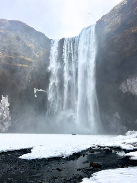      Full view of Seljalandsfoss waterfall cascading from a cliff amid swirling mist
  