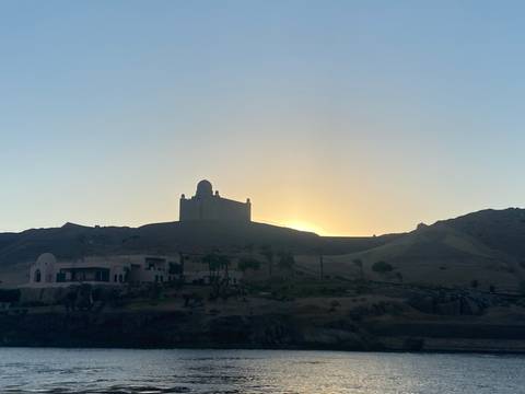       Silhouette of the Aga Khan Mausoleum on a desert ridge at sunrise above the Nile.
  