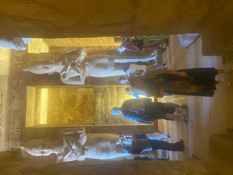       Interior of Abu Simbel temple crowded with visitors under warm artificial lighting.
  