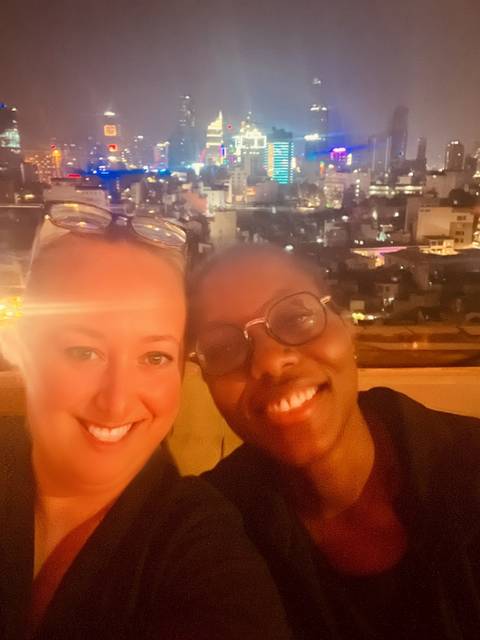       Selfie of two women against a blurred backdrop of city lights at night.
  
