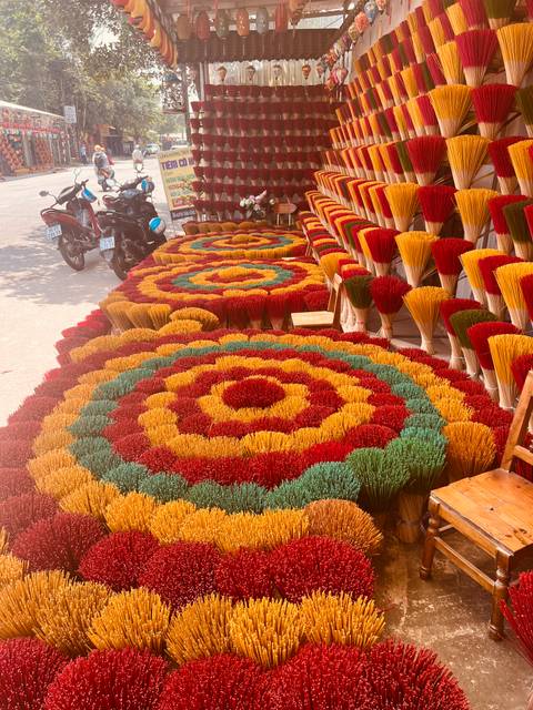       Brightly colored incense sticks arranged in circular patterns drying in the sun.
  