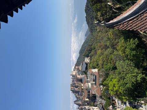       Hilltop fantasy castle complex rises above lush forest with a sea of clouds in the distance at Ba Na Hills.
  
