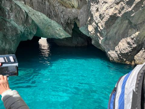       Turquoise water inside a sea cave with bright sunlight illuminating the entrance
  