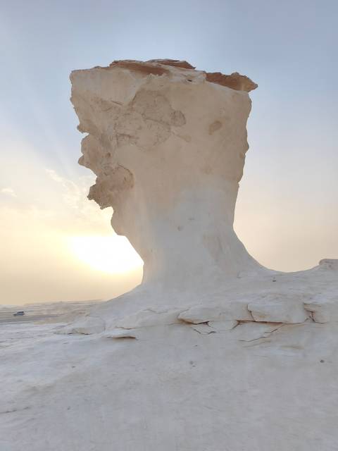       Striking white limestone mushroom rock formation silhouetted against a low desert sun
  