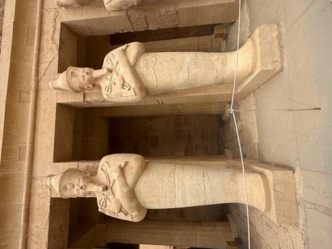       Two colossal standing pharaoh statues with crossed arms at the Temple of Hatshepsut.
  