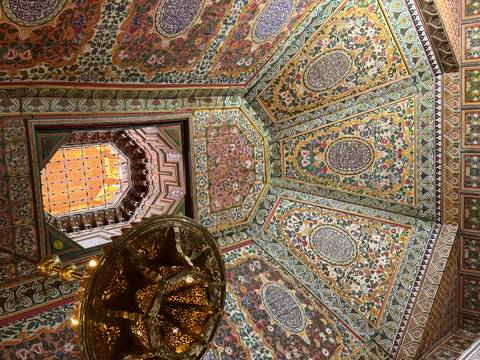       Opulent painted ceiling and ornate lantern inside a historic Moroccan palace
  