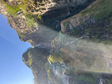       Tall waterfall plunging down a rocky cliff with sunlight rays creating misty beams
  