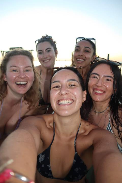       Selfie of five smiling young women, wet from swimming, enjoying a sunny day together.
  