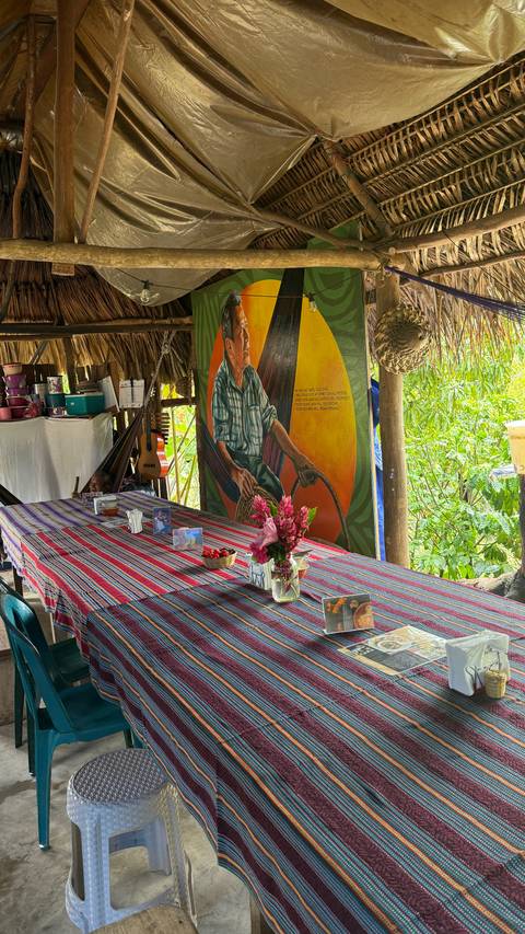       Colorful woven tablecloths, fresh flowers and artwork decorate an open-air rural dining area.
  