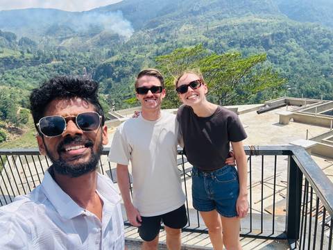      Selfie of three friends in sunglasses on a high terrace overlooking lush Sri Lankan hills.
  